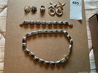 Full view of the silver jewelry including necklace, bracelet, earrings, and ring arranged on a flat surface