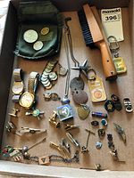 Overview of the collection showing watches, pins, tie clips, clothes brush, key chain, and bracelet in a box