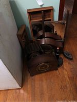 Group photo of mantel clocks, Coke bottles, and sad irons arranged on wooden floor showing overall condition and grouping.