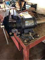 Full view of the Power Fist 4 inch multi purpose vise mounted on a red metal workbench