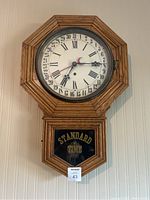 Front view of antique Brandon oak wall clock with Roman numerals, date ring and 'STANDARD TIME' glass door.