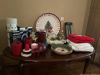 Full lot overview on table showing candles, dishes, ornaments, light strip box, and folded textiles
