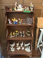 Overall view of wooden shelf filled with various small decorative and collectible figurines including birds, animals, and character statues.