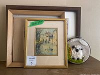 Three framed art pieces; two framed watercolor paintings and one circular framed needlework sheep.