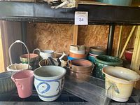 Overview of assorted garden planters and pots on a shelf showing variety of materials and colors.