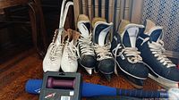 Three pairs of ice skates, dumbbell weights in a carrying case, and top portion of blue baseball bat visible