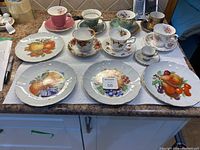 Full collection of teacup and plates, showing various floral and fruit patterns and gold trim details.