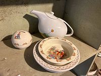 Overall view of Royal Doulton Bunnykins teapot money bank and three baby plates stacked