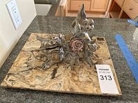 Top angle shot of the metal Shishi lion figurine on marble base, showing the lion holding a metal rod and detailed colored accents.