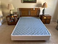 Full view of double/queen bed frame with mattress, two nightstands, and lamps in a bedroom setting.