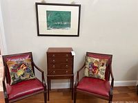 Overall view of two armchairs flanking side table with framed print above