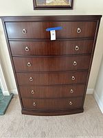 Front view of tall wooden dresser showing six drawers and metal ring pulls
