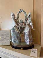 Frontal view of two women figurine on display base with certificate and lot number visible
