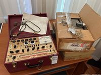 Overall view of tube tester and cardboard box of vacuum tubes on table