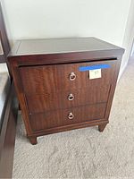 Front view of dark brown wooden nightstand with drawers closed