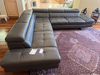 L-shaped gray leather sectional couch with tufted cushions, viewed from corner angle