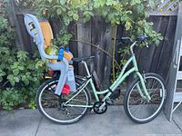 Full view of green Raleigh bicycle with rear child seat and helmet