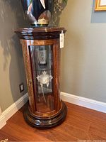 Front view of closed curio cabinet with top vase and floral arrangement