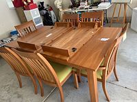 Table top with two leaves placed face down showing hinge hardware and matching wood grain