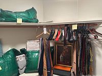 Overall view of hanging ties, bedding packs and framed painting on shelf.