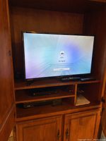 Samsung 32-inch television powered on showing 'No Signal' screen, located inside wooden cabinet.