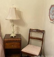 Side view of wooden side table with lamp and pink upholstered chair corner