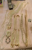 Photo showing assortment of pearl necklaces, beaded bracelets, and pearl earrings laid out on a surface.