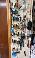 Full view of hand tools displayed on pegboard wall including screwdrivers, pliers, snips, clamps, measuring tools, cleaning tools, and packaged hardware.
