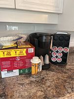 Photo of the Keurig machine on countertop with boxes of Keurig pods, French press, and reusable pods visible