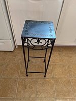 Black metal side table with decorative cutouts top view and side frame detail