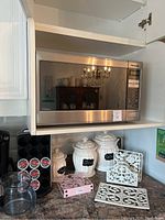 Front view of Panasonic The Genius microwave installed above kitchen counter showing keypad and display panel.