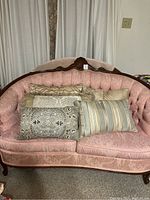 Six throw pillows arranged on pink vintage couch showing color, pattern, and condition of pillows.