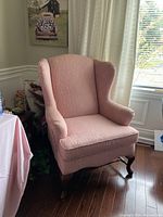 Front view of pink wingback armchair showing upholstery and cushion.