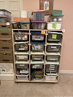 Full view of wooden organizer with multiple plastic bins containing various craft and teacher supplies in labeled compartments. Bins stacked on top.