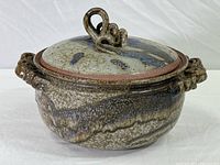 Full view of hand-formed art pottery covered casserole showing overall shape, glaze color, and side handles