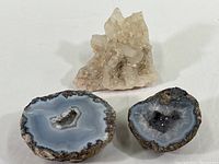 Two polished geode slices and one quartz crystal cluster displayed together on white background.