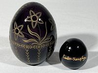 Two Russian collectible glass eggs on white background showing size difference and decorative details