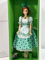 Full view of Barbie doll in box with green background and accessories.