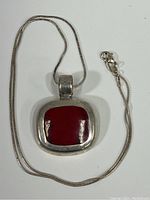 Full view of pendant on sterling silver chain laid flat on white background showing overall look of pendant and chain.