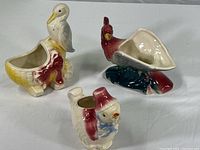 Lot overview showing three ceramic planter pots shaped as animals: stork, parrot, and a bird with a hat.