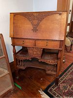 Front view of carved oak drop-front secretary desk showing overall appearance and decorative motif.