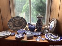 Wide view of all dishware and ceramics displayed on wooden surface near window, showing variety and scale of items
