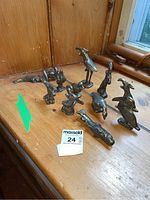 Full view of the eleven brass animal paperweights displayed on wooden surface, showing different animal shapes and sizes