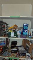 Photo showing shelves stocked with steel wool, lightbulbs, boxed hardware components, and various tools including stapler and glue.