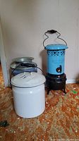 Photo of the blue Hot Blast heater alongside two vintage cans on an orange patterned floor.