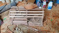 Wooden lobster trap with rope, vintage snow shoes with woven webbing, and wooden carved duck decoy on table showing lot contents