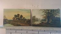 View of two vintage landscape paintings on canvas side by side on a mantle showing overall condition and size
