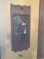 Full view of carved wood mirror featuring a man carrying fish and standing outdoors, with decorative carved frame.