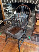 Front-right angled view of the antique Windsor arm chair showing the curved top rail, spindle backrest, shaped seat, and turned legs.