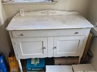 Front view of antique wooden buffet/sideboard painted white with visible crackled paint and wear showing age and vintage condition.